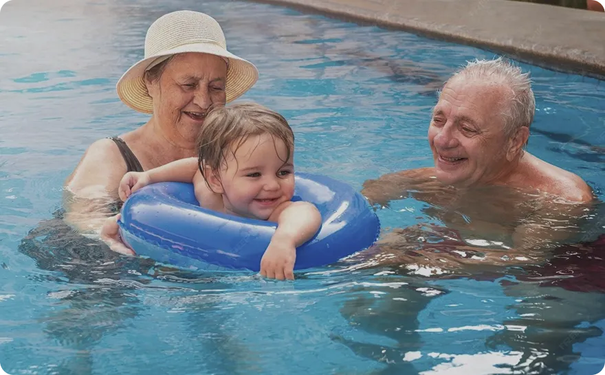 Bebé con flotador en la piscina junto a sus abuelos