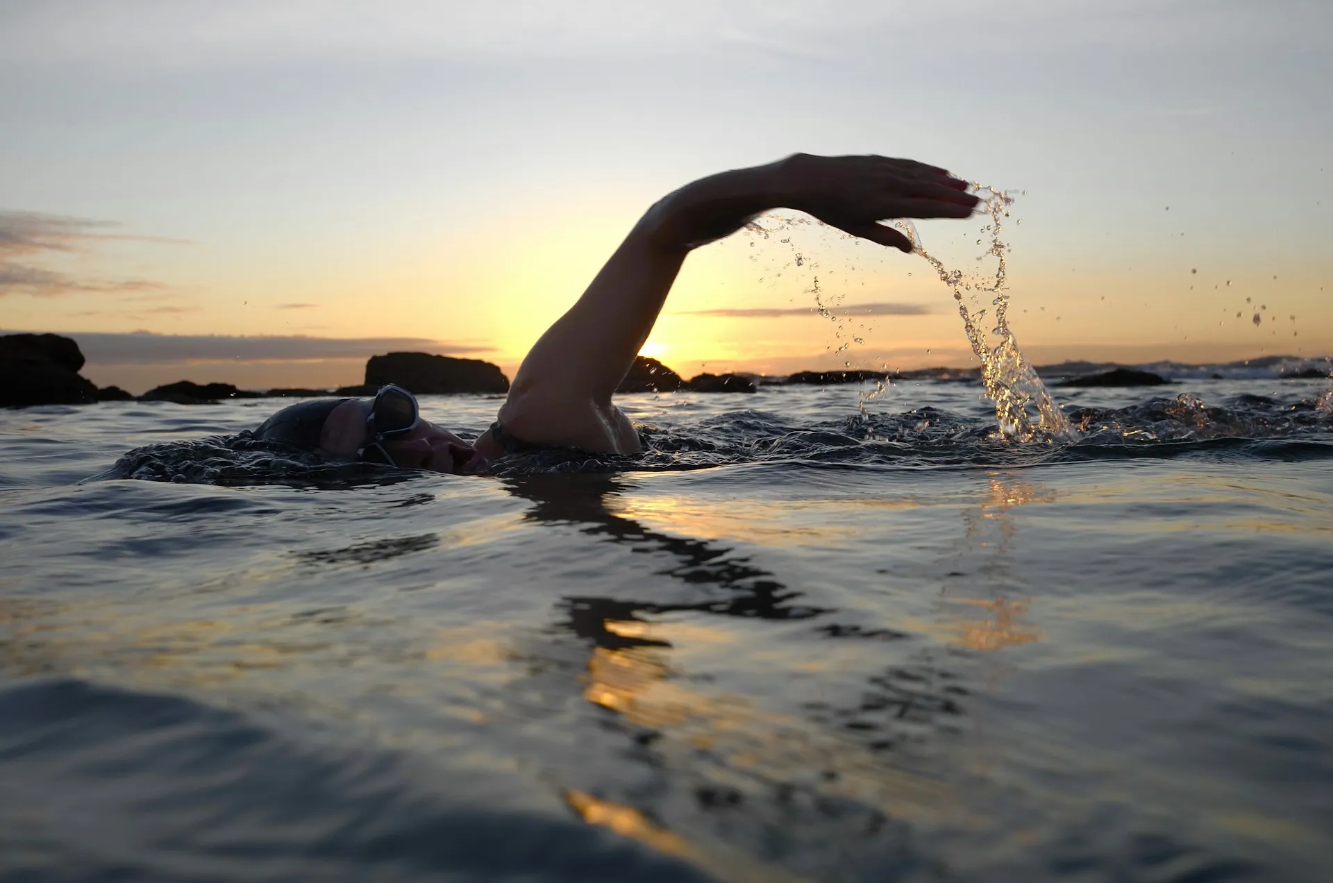 Brazada de un nadador al atardecer en el mar